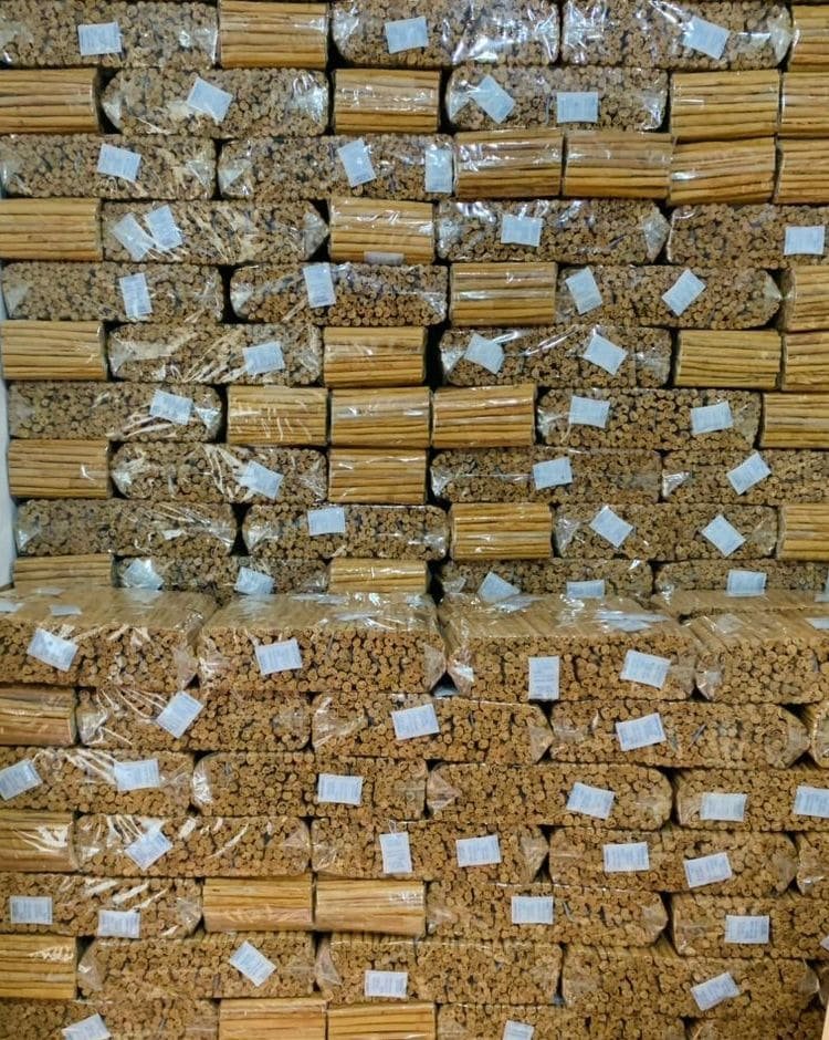 Sealed polythene bundles of cinnamon quills with lot labels stacked for dispatch